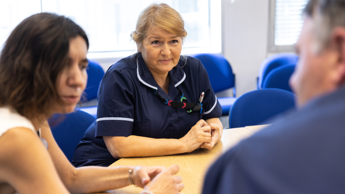Woman in healthcare role sitting at a table with two fellow colleagues