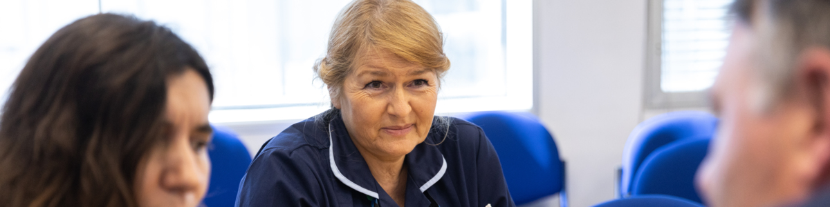 Woman in healthcare role sitting at a table with two fellow colleagues