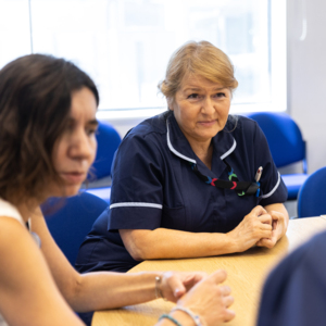Woman in healthcare role sitting at a table with two fellow colleagues