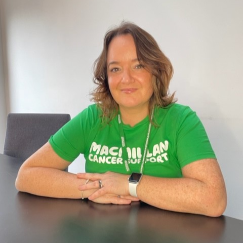 Photograph of Macmillan's HR Director, Jane Sey. She is looking at the camera and wearing a green t-shirt with the Macmillan logo on it.