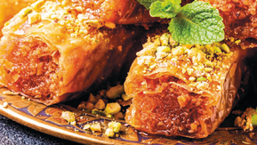 A stack of golden, flaky baklava pieces glistening with sweet syrup and sprinkled with crushed pistachios, mouth-wateringly sweet.
