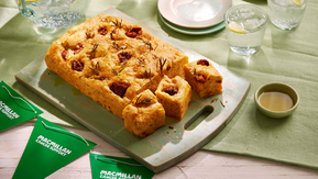 A tomato focaccia brad on a chopping board, cut into pieces ready to eat