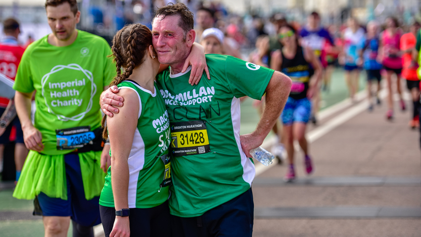 A father and daughter both wearing Macmillan running tops hugging at the end of a race