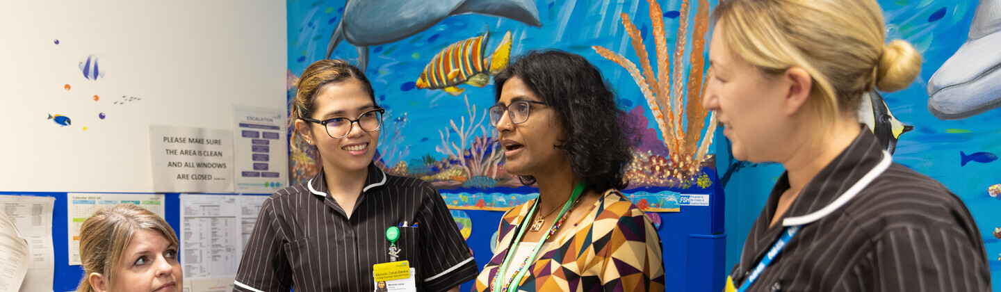 A consultant urologist is talking to 3 healthcare professionals 