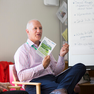 A doctor is showing a Macmillan leaflet to a group of people who are not in the photo