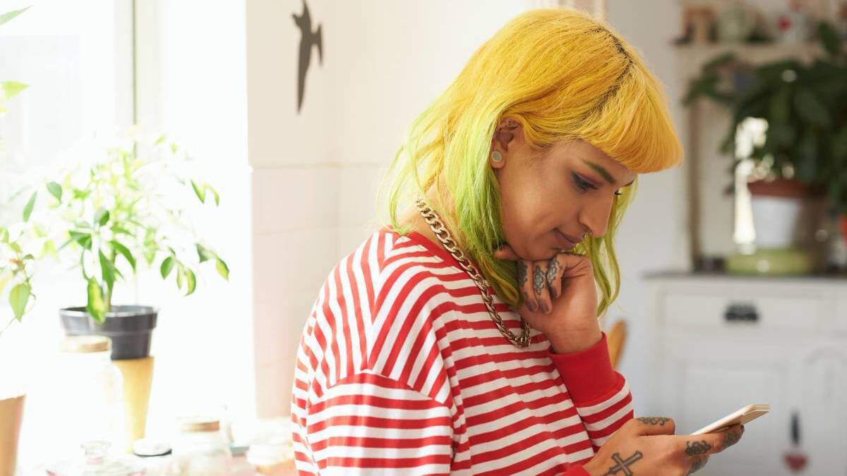 A lady with yellow hair looks at her mobile phone.