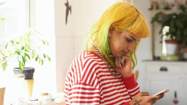 A lady with yellow hair looks at her mobile phone.