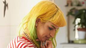 A lady with yellow hair looks at her mobile phone.