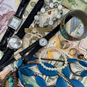 Different items like watches and jewellery are on top of different bank notes.
