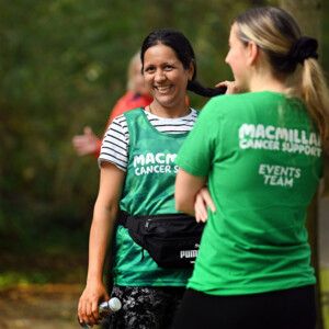 Two people are standing outside. They are wearing Macmillan branded tops. 