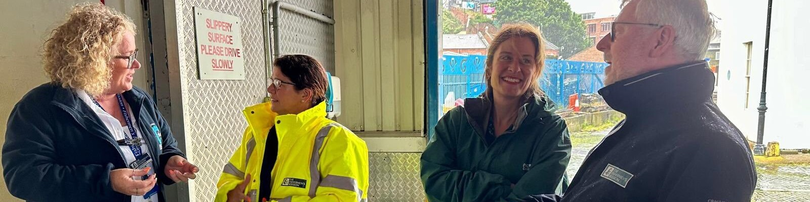 Four people standing together outside. They are talking to each other and not looking at the camera.
