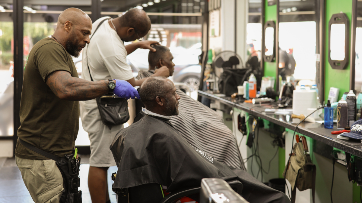 A Black man's barbers with men having their hair cut.