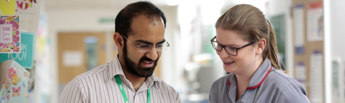 A male healthcare professional talks to a female healthcare professional.