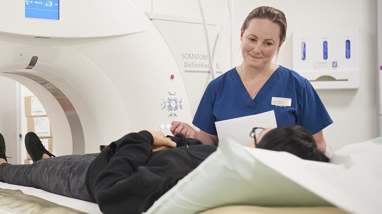 A healthcare professional with a patient before an MRI scan
