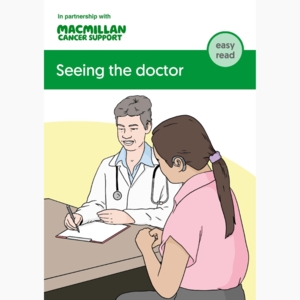 Two people are sitting down at a table. One person is a doctor. The doctor is wearing a white coat and they have a stethoscope around their neck. The other person is wearing a pink top. They have long dark hair tied in a pony tail. 