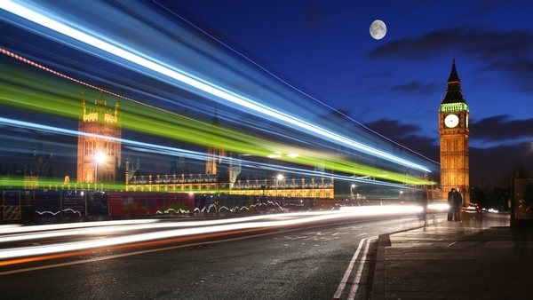 The image shows Big Ben and the UK Parliament building in London. The image has been taken so that the speed of cars and other vehicles passing by show a stream of light.
