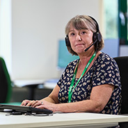 A woman wearing a telephone headset working on the Macmillan Support Line.