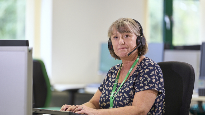 Andria, an advisor from the Macmillan Support Line, sitting at a computer wearing a headset for taking calls.