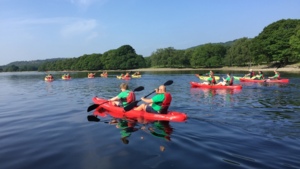 A group of people in two person kayaks are kayaking in a lake. Some of the kayaks are red and some are yellow. 