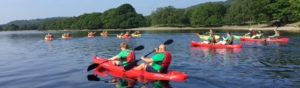 A group of people in two person kayaks are kayaking in a lake. Some of the kayaks are red and some are yellow. 