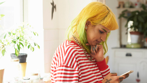 A women with yellow hair looks at her mobile phone.