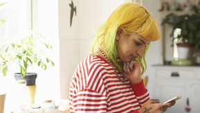 A women with yellow hair looks at her mobile phone.