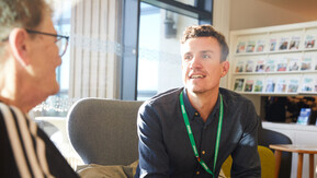 Healthcare professional in conversation with an older person seated across from him.
