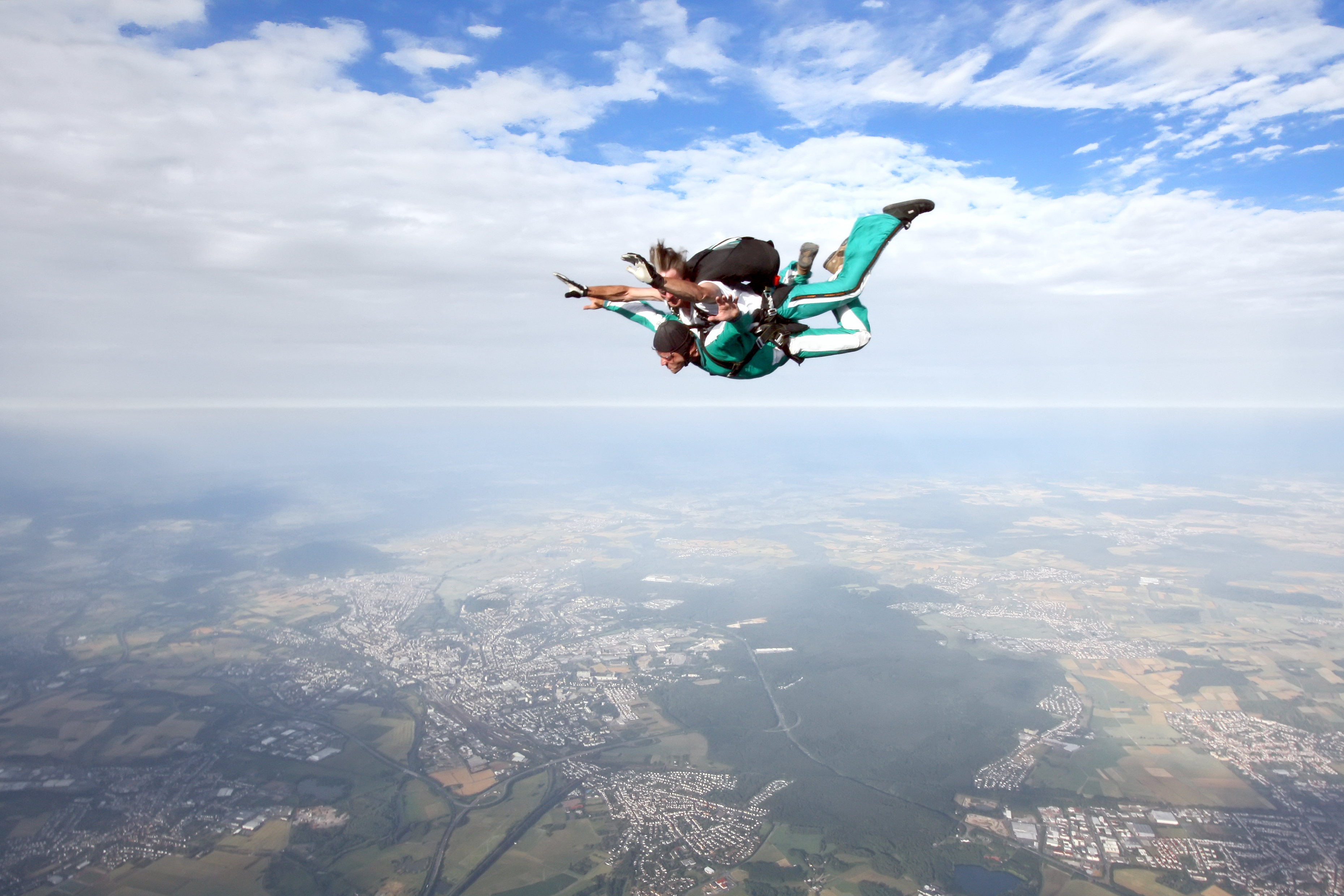 Two people strapped together in mid-air doing a tandem skydive.