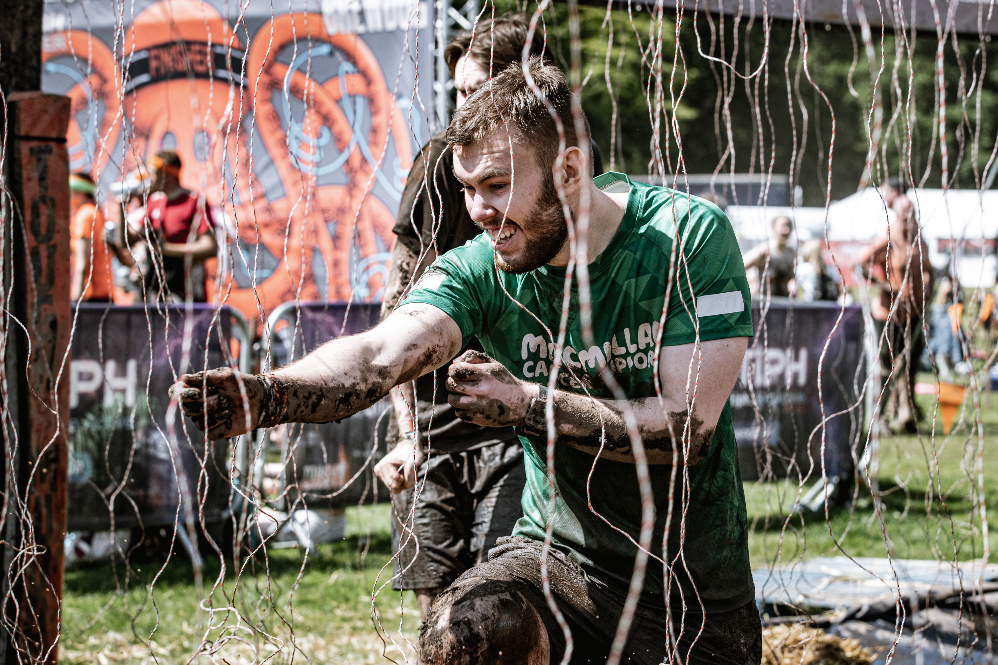 A man wearing a Macmillan t-shirt running through electric shock wires