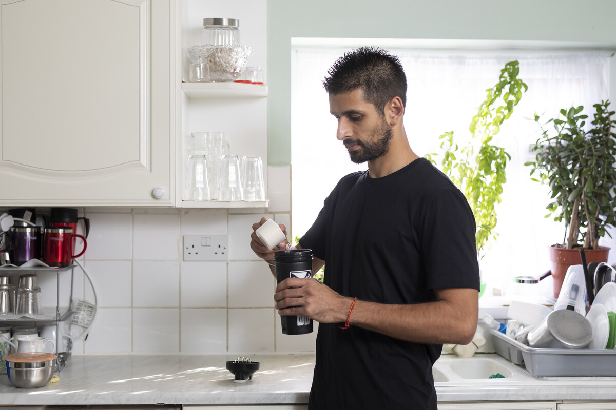 A man preparing a protein or healthy milkshake in his kitchen