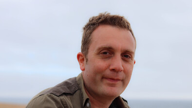 Alex Donohue is a Senior Digital Content Writer at Macmillan. He has short brown hair and is wearing a brown shirt. 