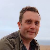 Alex Donohue is a Senior Digital Content Writer at Macmillan. He has short brown hair and is wearing a brown shirt. 