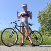 A woman sitting on a bike with her thumbs up