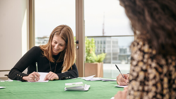 Two women sitting at a table signing cards