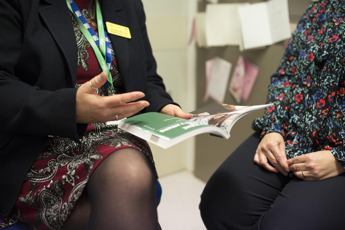 A Macmillan Professional giving an explanation while holding a Macmillan booklet