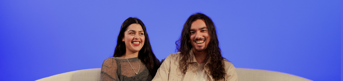 Lauren and her boyfriend, Danny are sitting on a sofa looking happy. He has his hand on her knee.