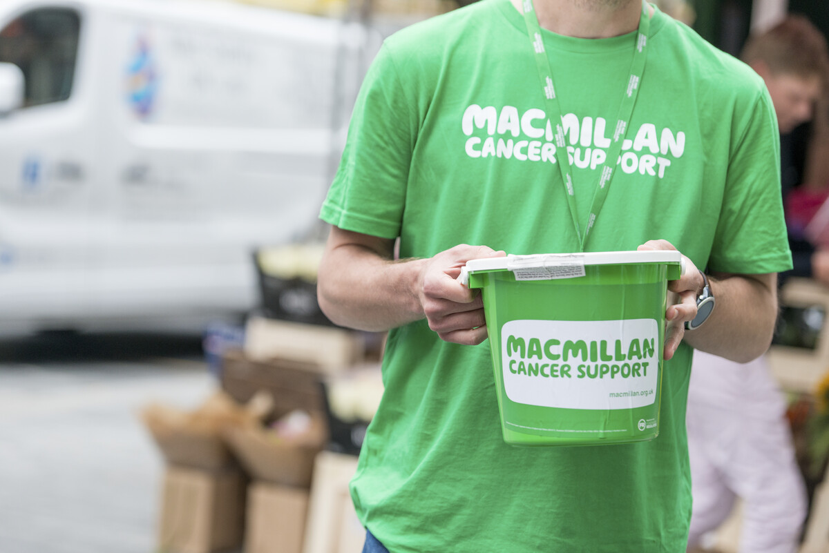 A person wearing a Macmillan t-shirt holding a fundraising bucket