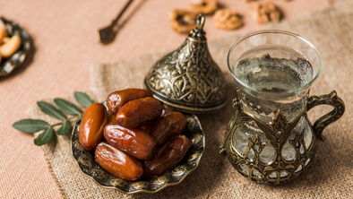 A table set with a bowl of dates and water in a decorative glass