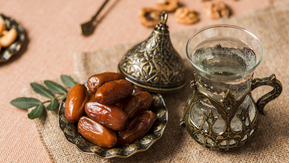 A table set with a bowl of dates and water in a decorative glass