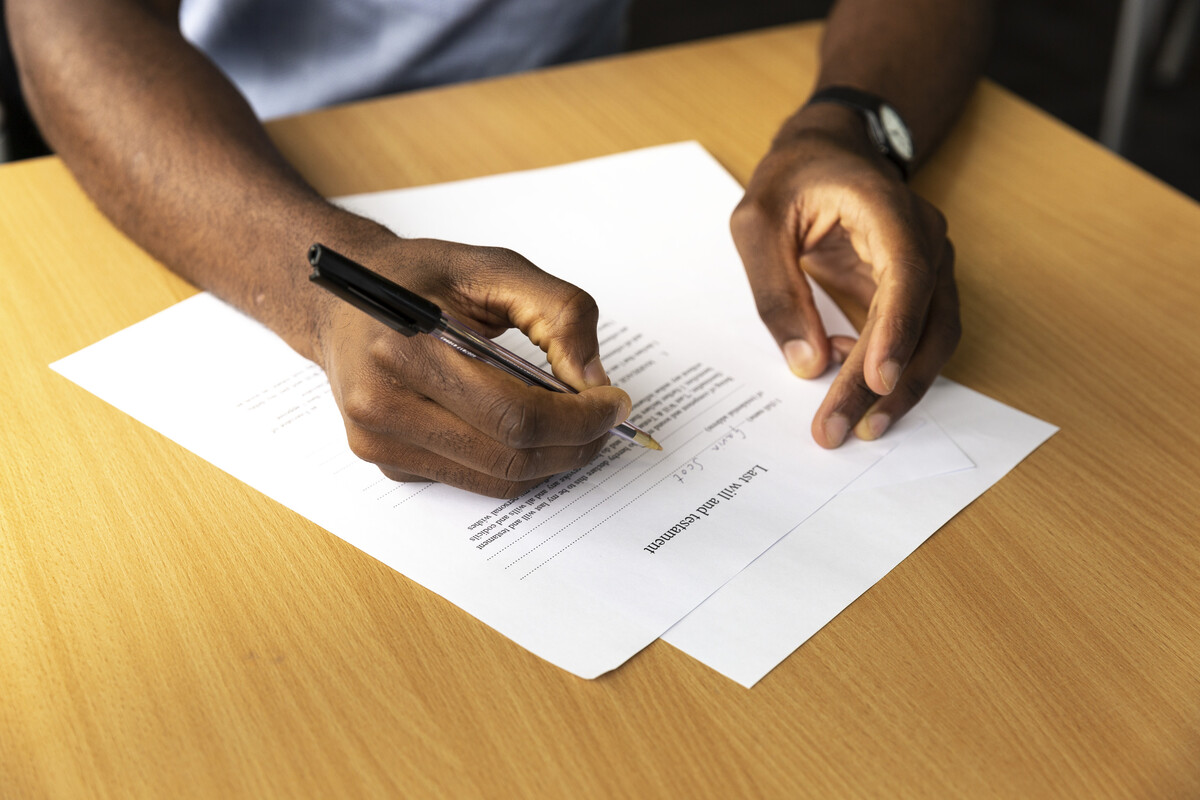 A close-up of man's hands writing a will