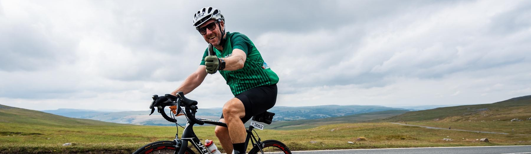 Man cycling wearing a Macmillan cycling jersey