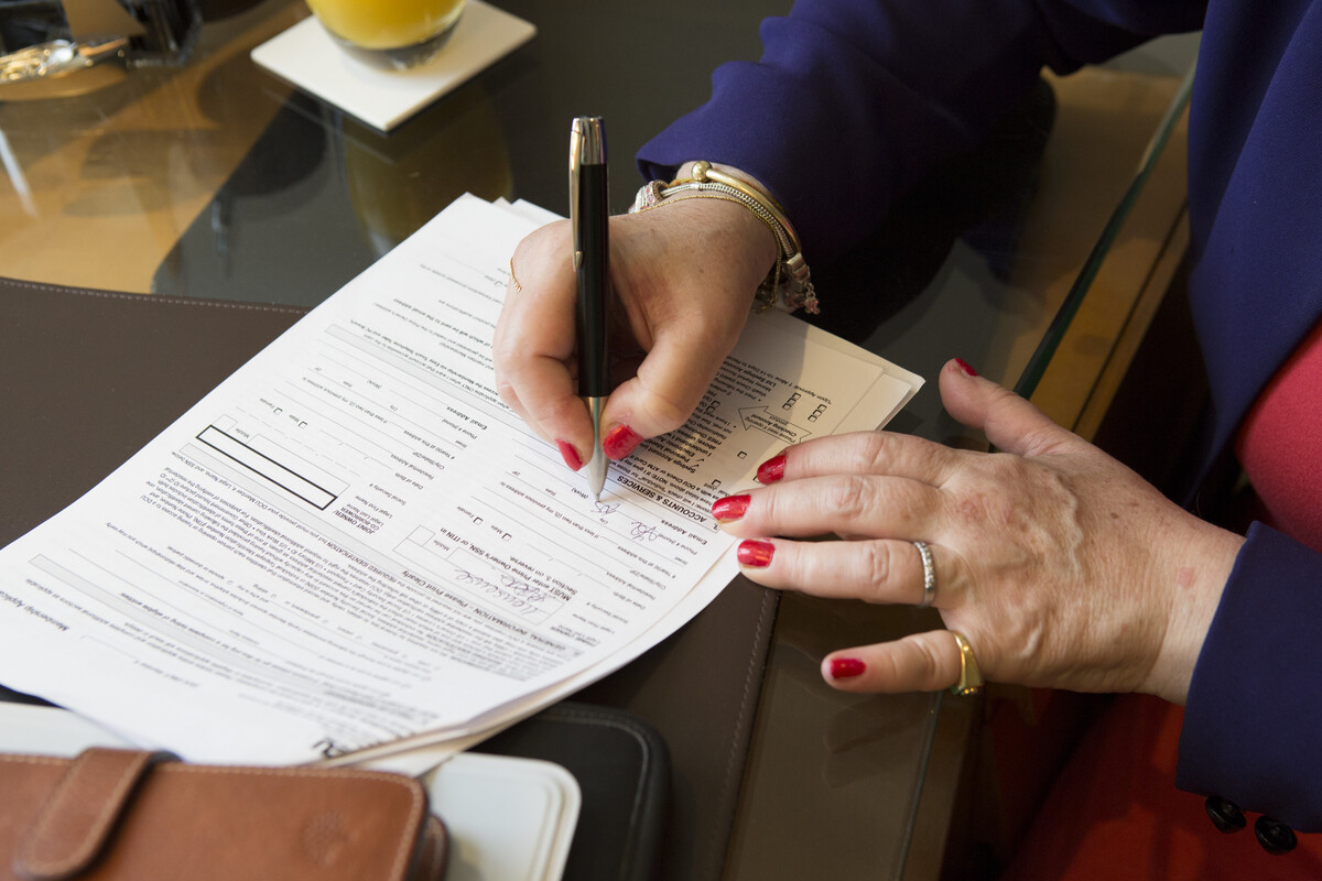 A close-up of a women's hands writing on an application form