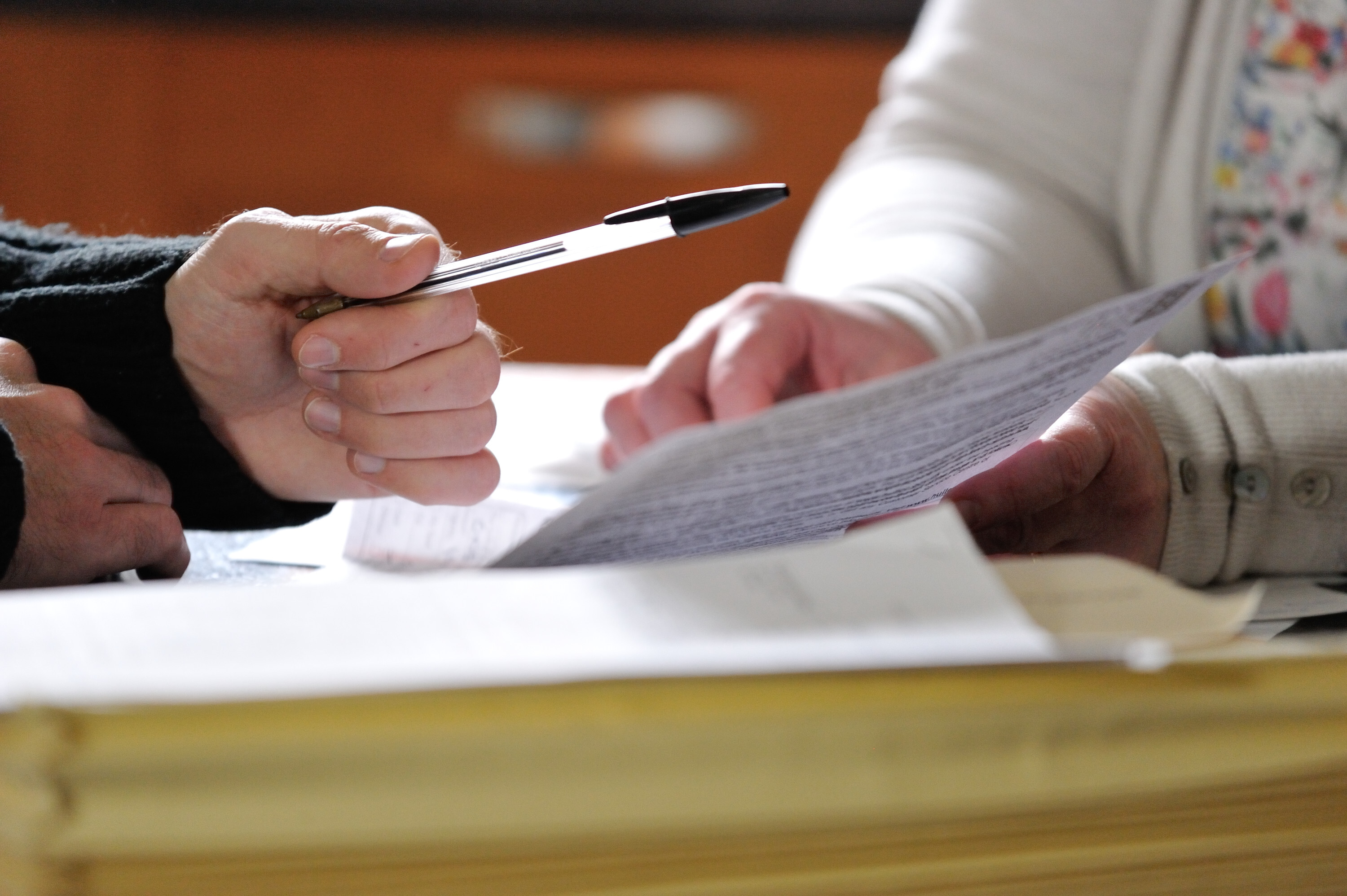 Close- up photo of two people's hands completing an application form