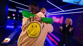 2 women hugging at a bowling alley.