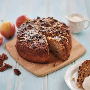 A scrumptious apple cake topped with a layer of crunchy pecan nut streusel. A slice of the cake reveals the moist, spiced apple filled sponge.