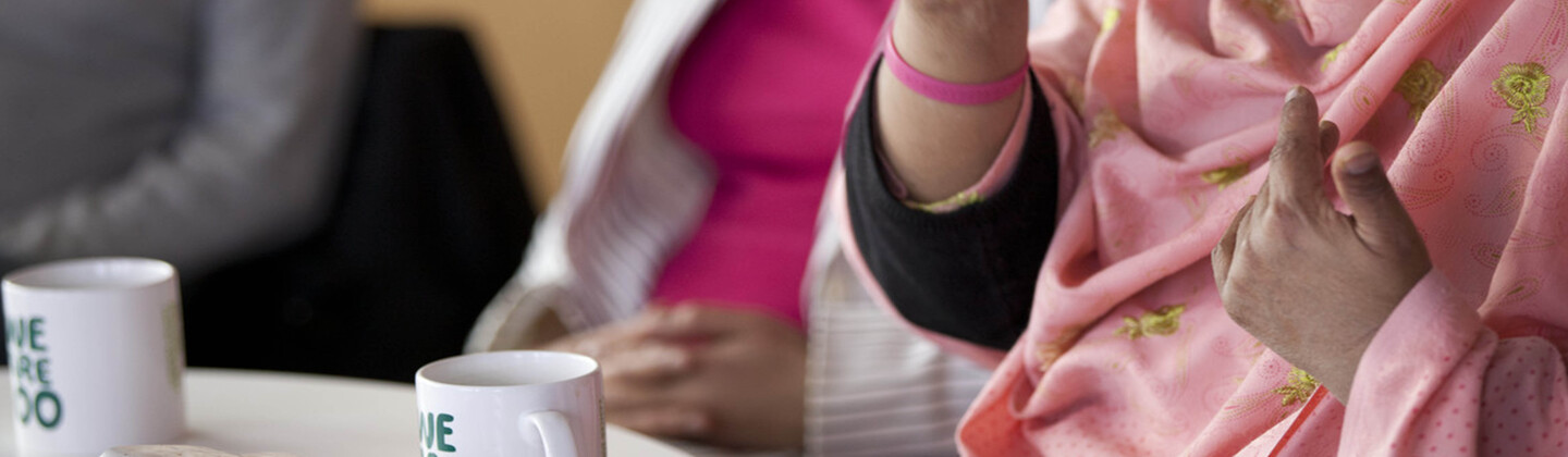 A group of people sitting around a table with mugs of tea.