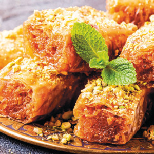 A stack of golden, flaky baklava pieces glistening with sweet syrup and sprinkled with crushed pistachios, mouth-wateringly sweet.