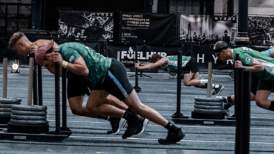 A group of people are participating in HYROX. They are pushing weight sleds across a gym floor.