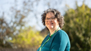 Claire from Macmillan Deaf Cancer Support project is standing outside and smiling at the camera. She is wearing a Macmillan lanyard around her neck.