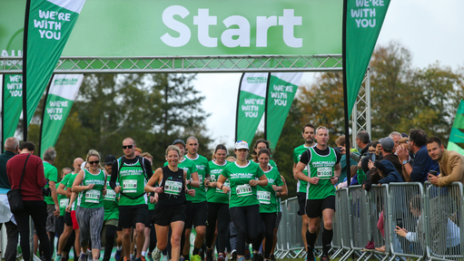 Lots of runners wearing Macmillan green coming over the start line